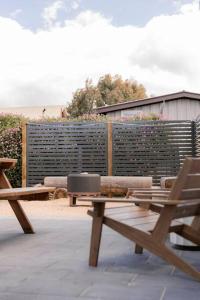 eine Terrasse mit zwei Bänken und einem Zaun in der Unterkunft Bay Hideaway Stieglitz in Saint Helens Island