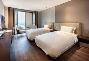 Postel nebo postele na pokoji v ubytování Jian Guo Hotel Yantai Phoenix Building