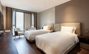 Postel nebo postele na pokoji v ubytování Jian Guo Hotel Yantai Phoenix Building