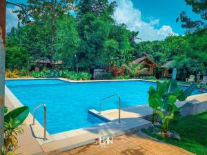 a large swimming pool with blue water and trees at Banlaw Garden Resort in Puerto Princesa City