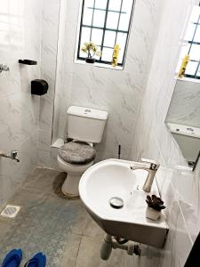 a white bathroom with a toilet and a sink at Pacho luxury homes in Kisumu +49 photos
