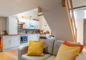 a living room with a couch and a kitchen at The Coach House - Cosy Retreat in Warwickshire! in Shottery