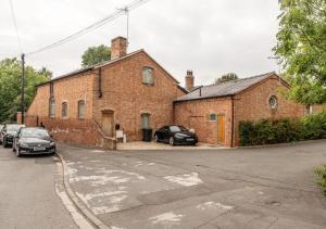 a brick building with cars parked in front of it at The Coach House - Cosy Retreat in Warwickshire! in Shottery