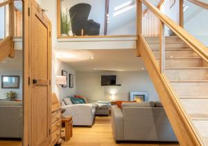 a living room with a staircase leading up to a loft at The Coach House - Cosy Retreat in Warwickshire! in Shottery