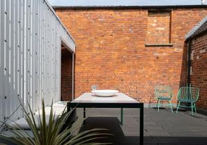 a patio with a table and chairs and a brick wall at The Emporium - Stylish 2BD in central Winchcombe in Winchcombe