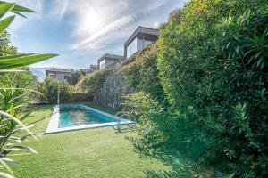 a garden with a swimming pool next to a wall at Bellavista Laglio Lagoon B by Italian Apartments in Laglio