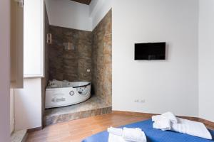 a bathroom with a tub and a tv on a wall at Casa Papaccio Apartment & Spa By Dimorra in Naples +37 photos