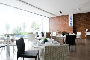 a dining room with white tables and chairs at Mansion28 Dharmawangsa Serviced Apartment in Jakarta