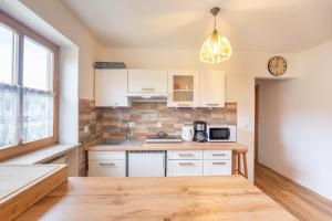 a kitchen with white cabinets and a clock on the wall at Apartman Arberblick 20 in Bayerisch Eisenstein