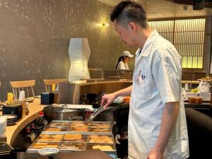 a man preparing food in a restaurant kitchen at LiveZen Bangkok Sukhumvit in Khlong Toei