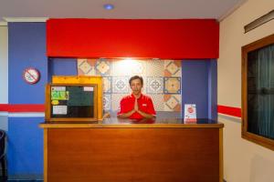 a man sitting at a counter in a room at Hotel O Riau Near Gedung Sate Formerly Patradisa in Bandung