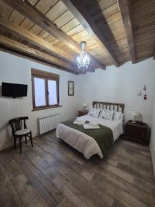 sypialnia z łóżkiem i telewizorem oraz drewnianym sufitem w obiekcie Casa Rural Rincón w mieście El Cabaco