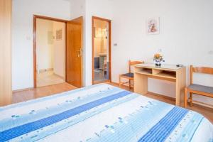 a bedroom with a large bed with a desk and a desk at Apartment and Rooms Luka in Vrbnik