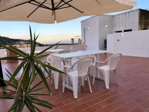 een patio met witte tafels en stoelen en een parasol bij Casa Vacanze Sunshine in Salerno