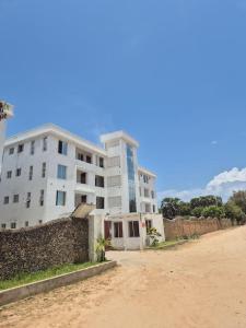 a large white building on the side of a dirt road at Daffi giraffi House in Malindi