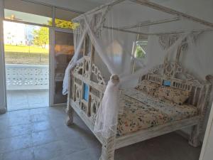 a bedroom with a white bed with a canopy at Daffi giraffi House in Malindi +24 photos