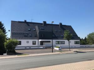 een groot wit gebouw met een zwart dak bij Ferienwohnung Wolkenplatz in Winterberg
