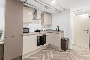 a kitchen with white cabinets and a refrigerator at The Lister Gate Studios in Nottingham +19 photos