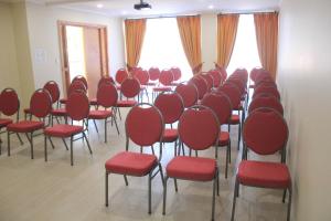 a room with red chairs and tables and windows at Hotel Plaza Pinto in Los Ángeles