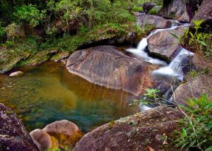 a stream of water with rocks in a river at Pousada da Gruta in Visconde De Maua