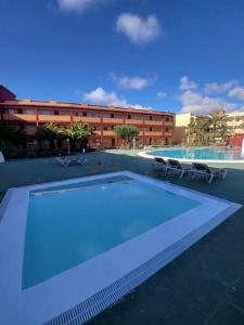 Una piscina con dos sillas y un edificio. en Bella, en Parque Holandes