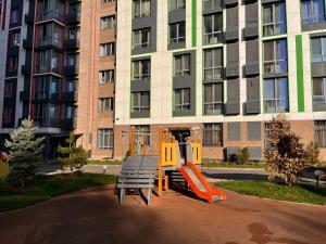 un parque infantil frente a un edificio de apartamentos en Raimbek19-45 Residence 1BR nearby metro & drinking water as a gift, en Almaty