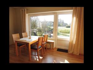Wesselburener DeichhausenにあるFerienwohnung Lükeのテーブルと椅子と窓のあるダイニングルーム