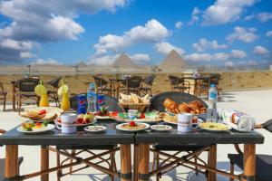 una tavola con cibo sopra con vista sulle piramidi di PYRAMIDS guest house a Il Cairo