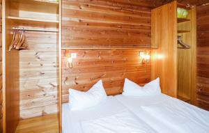 ein Schlafzimmer mit einem weißen Bett an einer Holzwand in der Unterkunft Ferienhaus Erms 87 in Hayingen