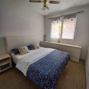 a bedroom with a bed with a blue comforter and a window at Bella in Parque Holandes