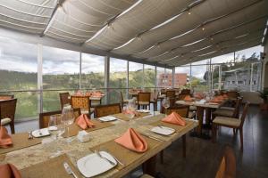 a restaurant with tables and chairs and large windows at Hotel Stubel Suites & Cafe in Quito