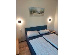 a bedroom with a blue bed and a painting on the wall at Ferienhaus "Unser neues Haus" in Trassenheide +19 photos