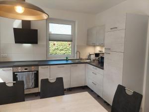 a kitchen with white cabinets and a large window at Ferienhaus "Unser neues Haus" in Trassenheide