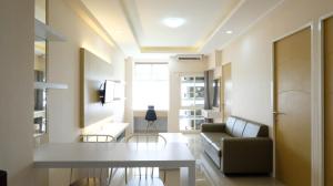 a living room with a table and a couch at Elegant and Spacious 3BR at Bale Hinggil Apartment By Travelio in Medokanayu