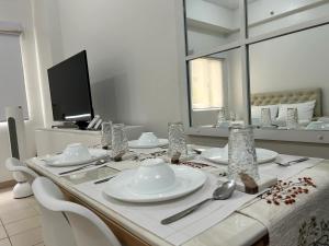 a table with white plates and utensils and a mirror at JK Suites Cheer B126 in Marilao
