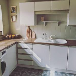 a kitchen with white cabinets and a sink at Willow Cottage in Rye
