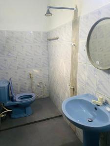 Un baño con un inodoro azul y un lavabo. en Berg House Unawatuna, en Galle