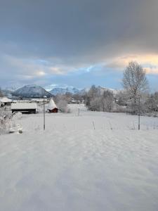 a field covered in snow with mountains in the background at Hus med 2 soverom in Sortland