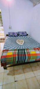 a bed with a colorful comforter with a clock on it at SUNNY CLIFF BEACH Stay in Arambol