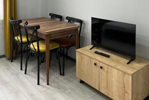 a wooden table with chairs and a flat screen tv at Ozn Suit Airport Hotel in Arnavutköy