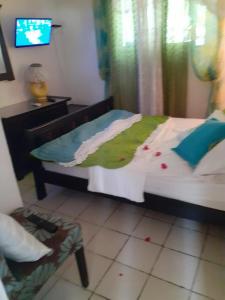 a bedroom with a bed and a tv in it at Bungalow charmant à Sainte-Rose avec piscine partagée in Sainte-Rose