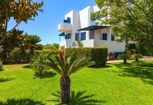 a palm tree in front of a white house at Villa Costa Haraki in Haraki