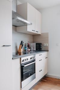 a kitchen with white cabinets and a stove top oven at Kleeoase - Infrarotsauna - Terrasse - Garten - kostenloser Parkplatz - BRIGHT Collection in Weinbach +20 photos