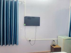 a tv on a wall in a room with a toilet at The La Renta Hotel & Spa in Hanoi