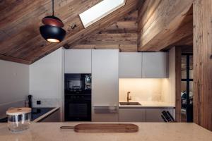 a kitchen with white cabinets and wooden ceilings at Antarès SIRIUS 301- Spacious ski inski out apartment in Méribel