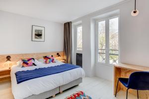 een slaapkamer met een bed, een bureau en ramen bij Hôtel Montholon in Parijs