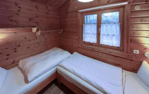 two beds in a wooden room with a window at Ferienhaus Neckar 71 in Hayingen