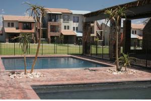 a swimming pool with two palm trees next to a fence at Luxuriously finished 2 bedroom in Midrand