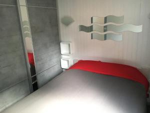 a small bedroom with a red bed and a mirror at Chalet orange naturiste la Jenny in Le Porge +19 photos