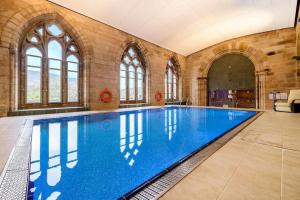 a large swimming pool in a large room with windows at Glen Mor Apartment with pool on site in Fort Augustus